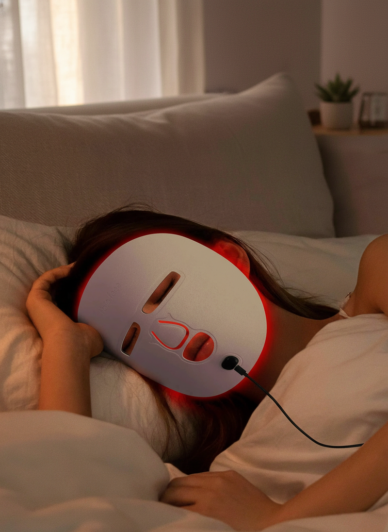 A person with diverse representation relaxing at home, wearing the LED Face Mask Facial Care Tool with red light therapy.